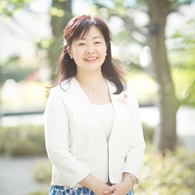 写真:春の日差しの中の笑顔。胸にハートブローチ