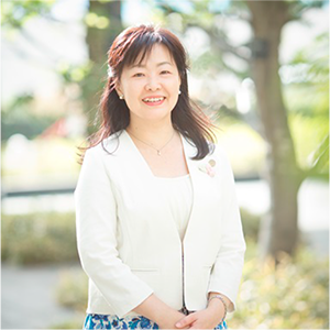 写真:春の日差しの中の笑顔。胸にハートブローチ